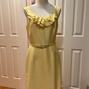 Sleeveless dress with ruffles around neckline. Shoulders are gathered.